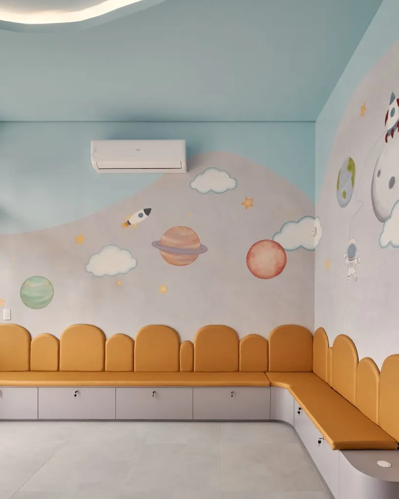 Sala de espera temática espacial da Clínica Majolí, com banco estofado e ilustração de planetas